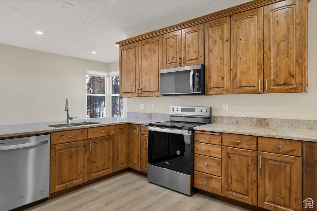 Kitchen with stainless steel appliances, brown cabinetry, and a sink