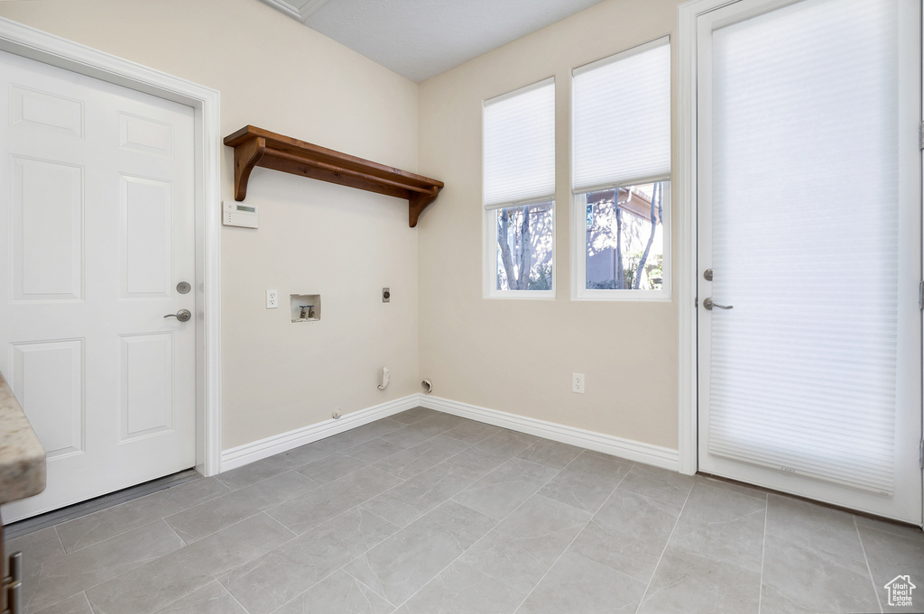 Laundry area featuring laundry area, baseboards, hookup for a washing machine, electric dryer hookup, and light tile patterned flooring