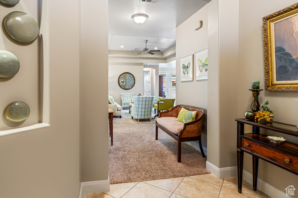 Corridor with light tile patterned floors, baseboards, and light colored carpet