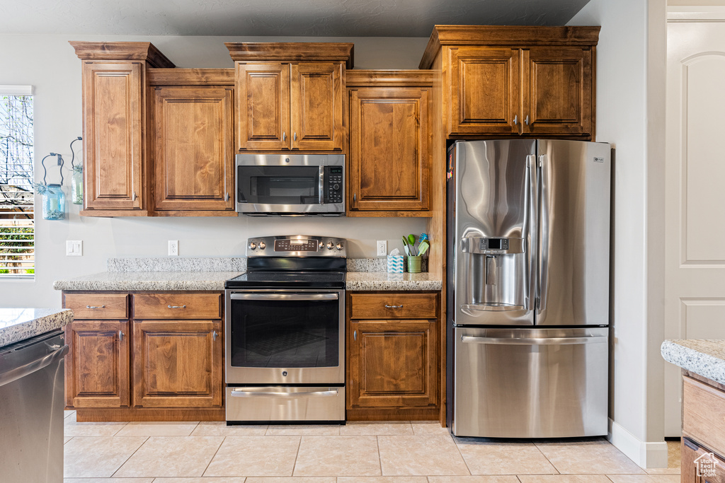 Kitchen featuring appliances with stainless steel finishes, a wealth of natural light, and light stone countertops