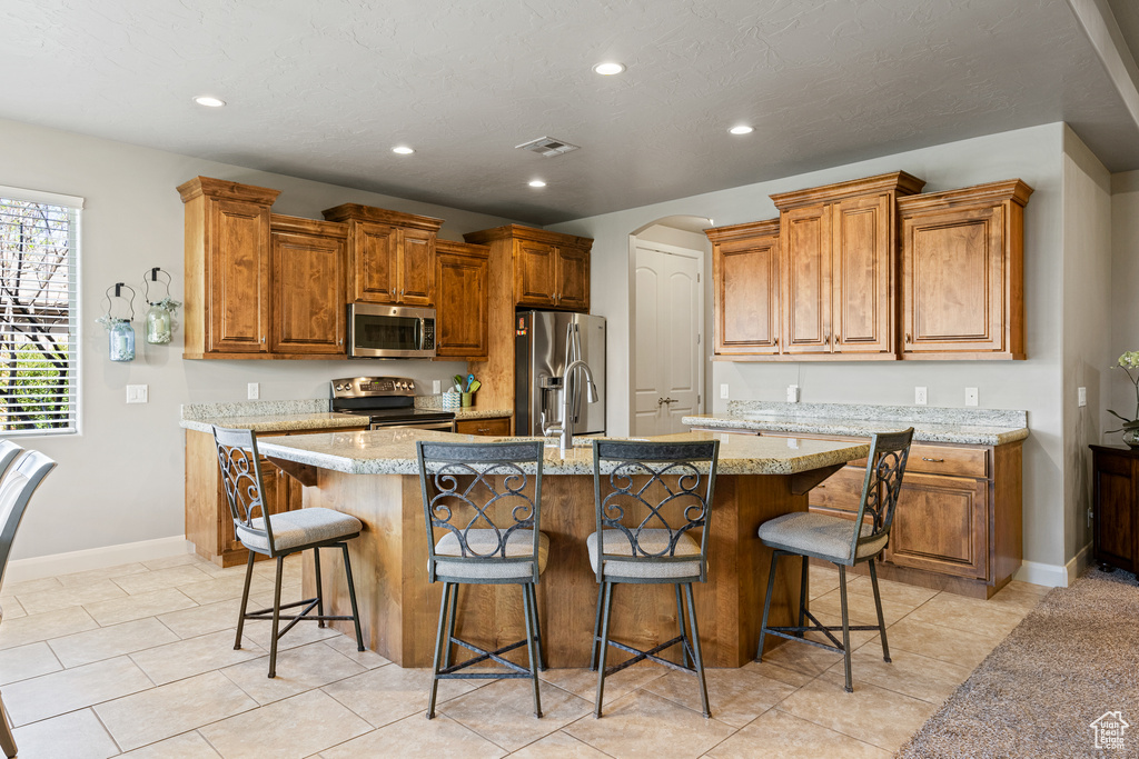 Kitchen featuring a kitchen island with sink, recessed lighting, visible vents, appliances with stainless steel finishes, and a kitchen bar