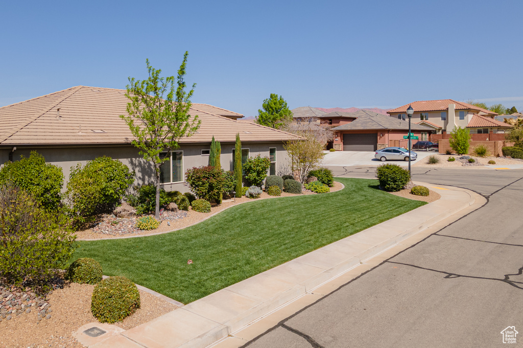 View of front facade featuring a tiled roof, a front yard, a residential view, and stucco siding