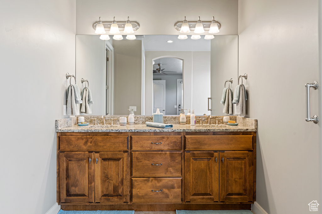 Bathroom with ceiling fan, double vanity, a sink, and baseboards