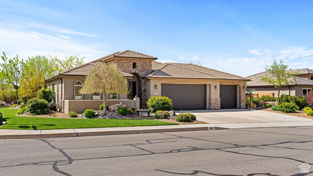 View of front of home featuring driveway, stone siding, an attached garage, and stucco siding