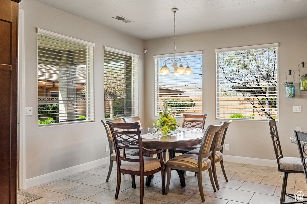 Dining space featuring light tile patterned floors, baseboards, visible vents, and a chandelier