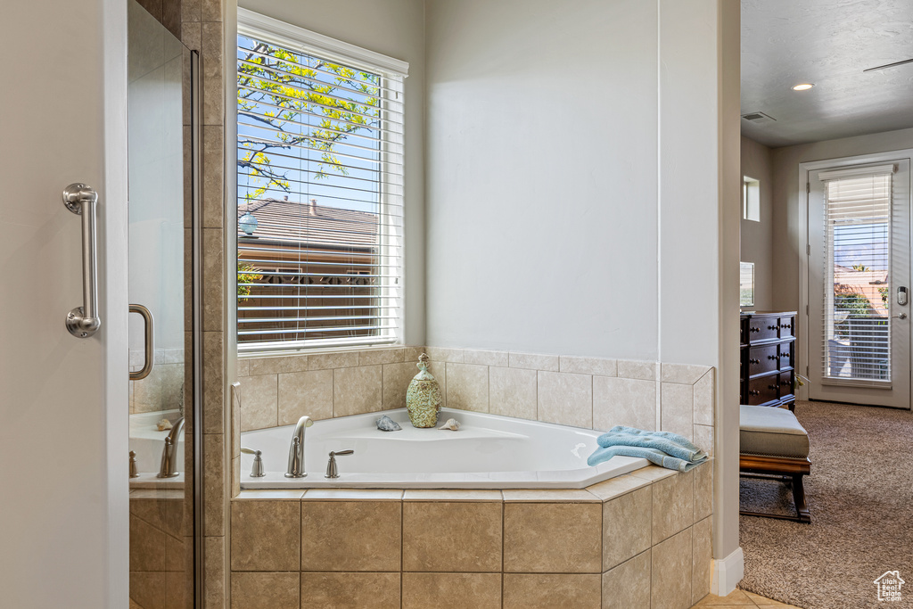 Bathroom with visible vents, a healthy amount of sunlight, a garden tub, and a shower stall