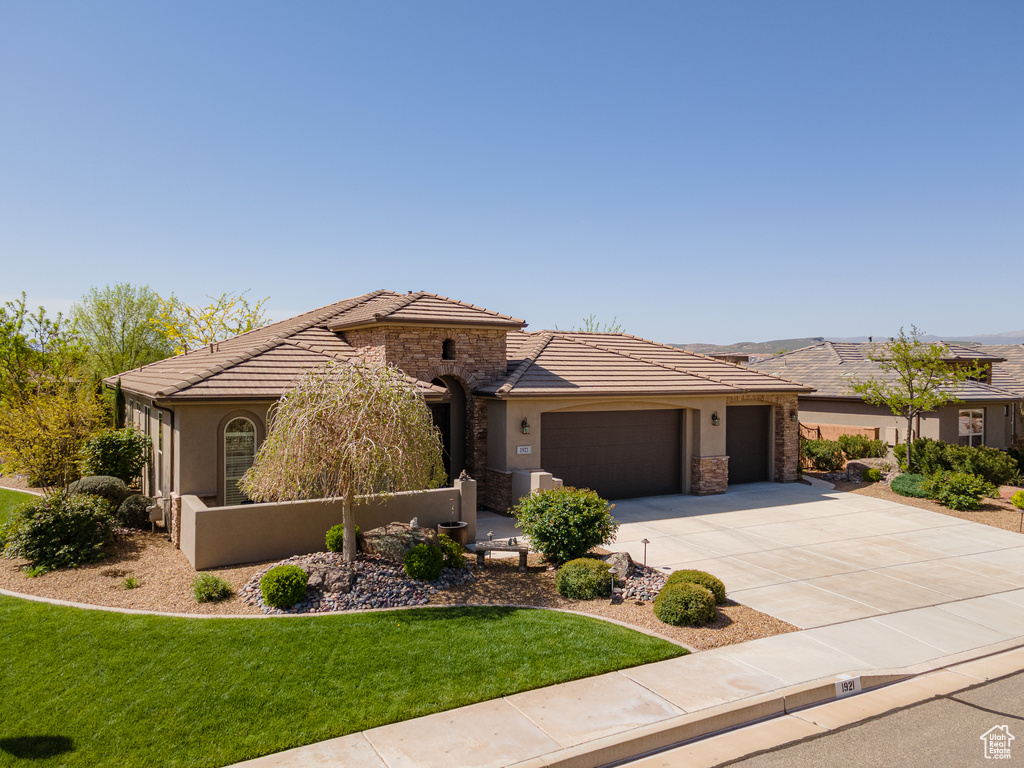 View of front of home featuring a garage, stone siding, driveway, and stucco siding