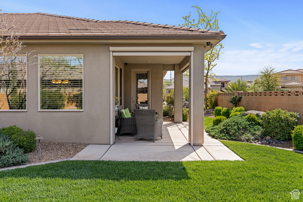 Exterior space with a patio, a tile roof, fence, a lawn, and stucco siding