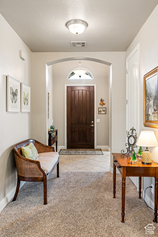 Entrance foyer with arched walkways, carpet, visible vents, and baseboards