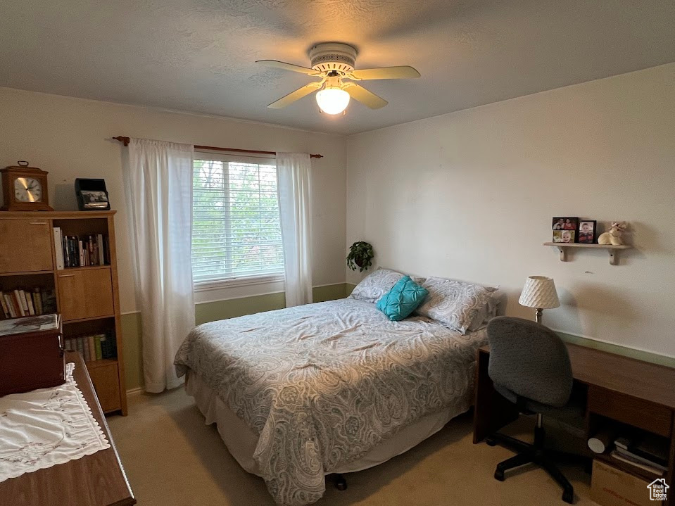 Bedroom with a ceiling fan, light carpet, and baseboards