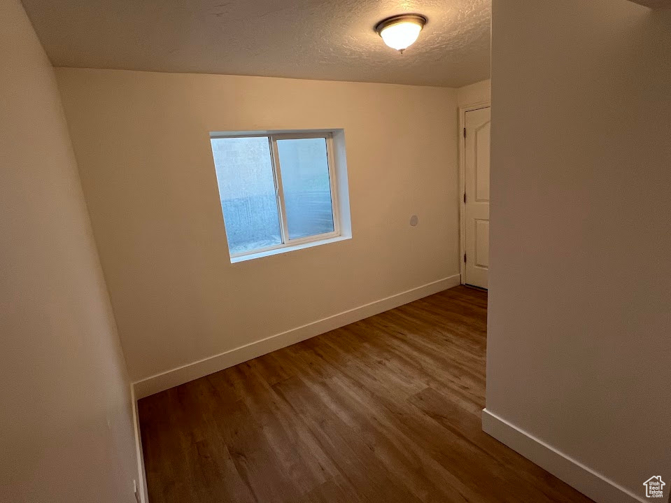 Empty room featuring baseboards, a textured ceiling, and wood finished floors