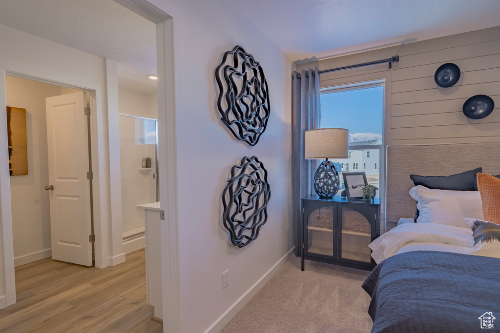 Bedroom with light wood-style floors, connected bathroom, and baseboards