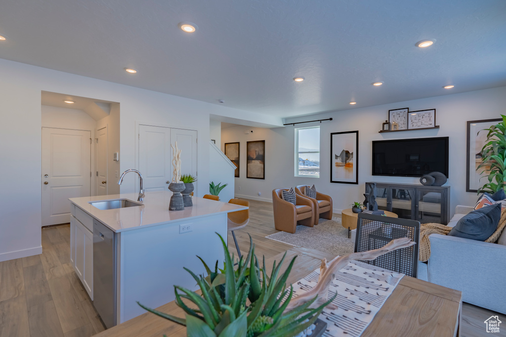 Kitchen featuring recessed lighting, light wood-style flooring, open floor plan, a sink, and dishwasher