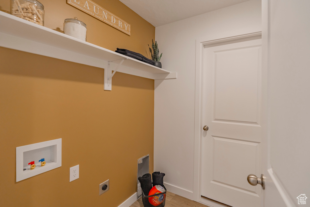 Washroom featuring hookup for an electric dryer, laundry area, washer hookup, baseboards, and light wood-type flooring