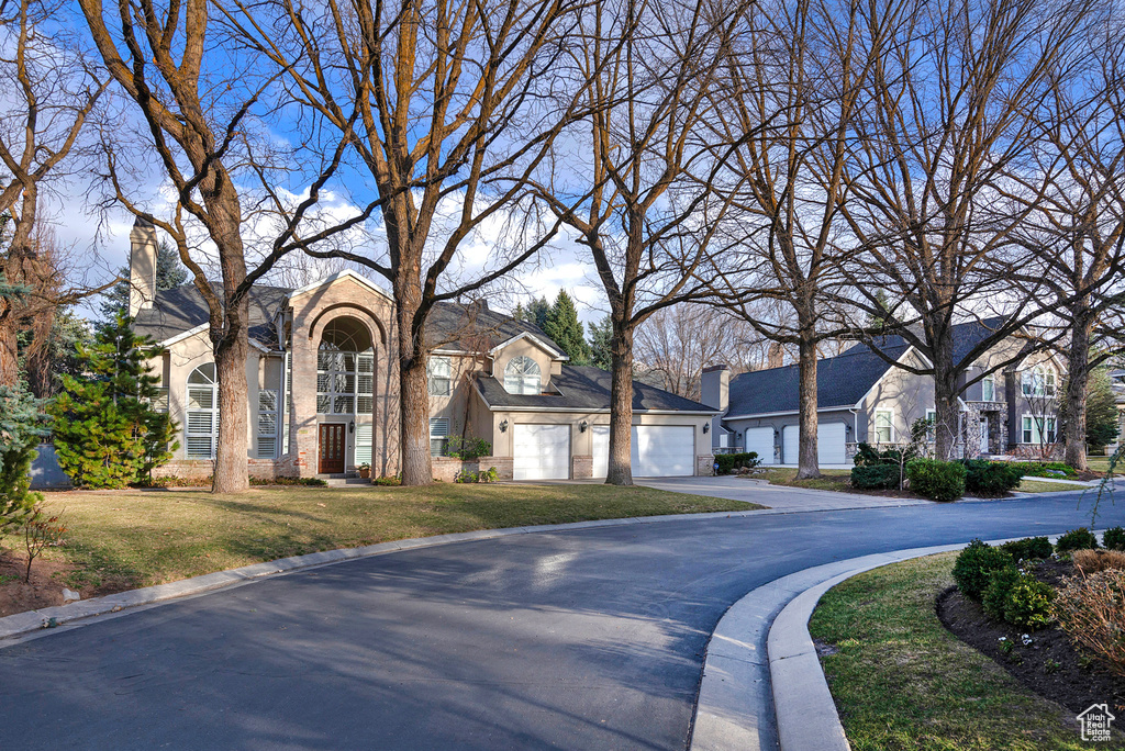 View of front of house with brick siding, a front yard, a garage, a residential view, and driveway