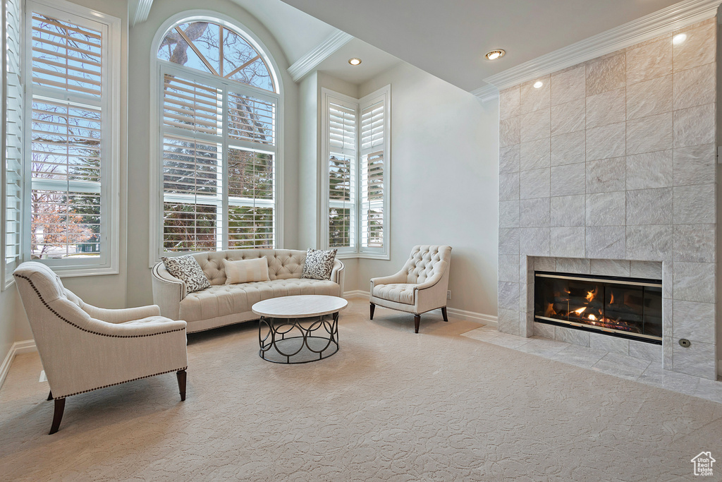 Carpeted living area with a wealth of natural light, a tile fireplace, crown molding, and baseboards