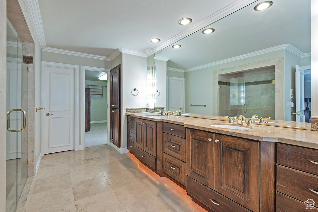 Bathroom featuring double vanity, a stall shower, and crown molding