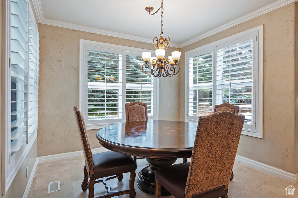 Dining space with an inviting chandelier, ornamental molding, and a wealth of natural light