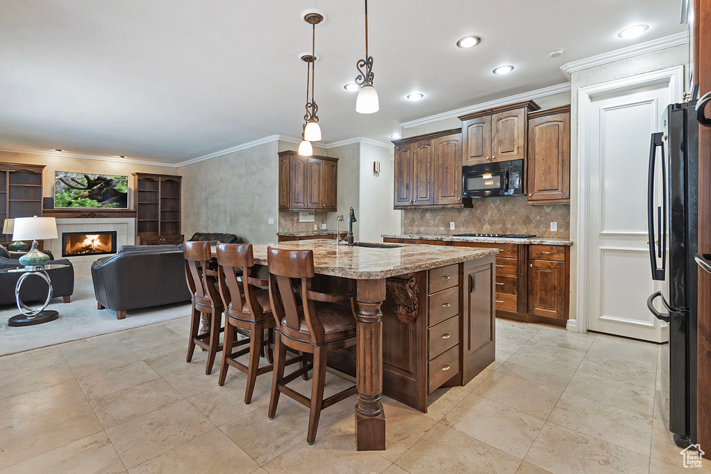 Kitchen with black microwave, stainless steel gas cooktop, a fireplace, a sink, and open floor plan