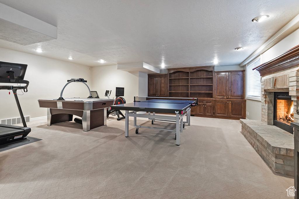 Game room with a textured ceiling, recessed lighting, light carpet, a fireplace, and baseboards