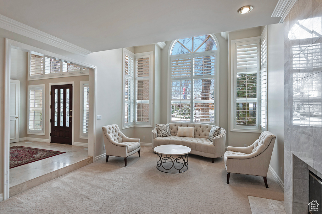 Interior space with a tile fireplace, crown molding, and baseboards