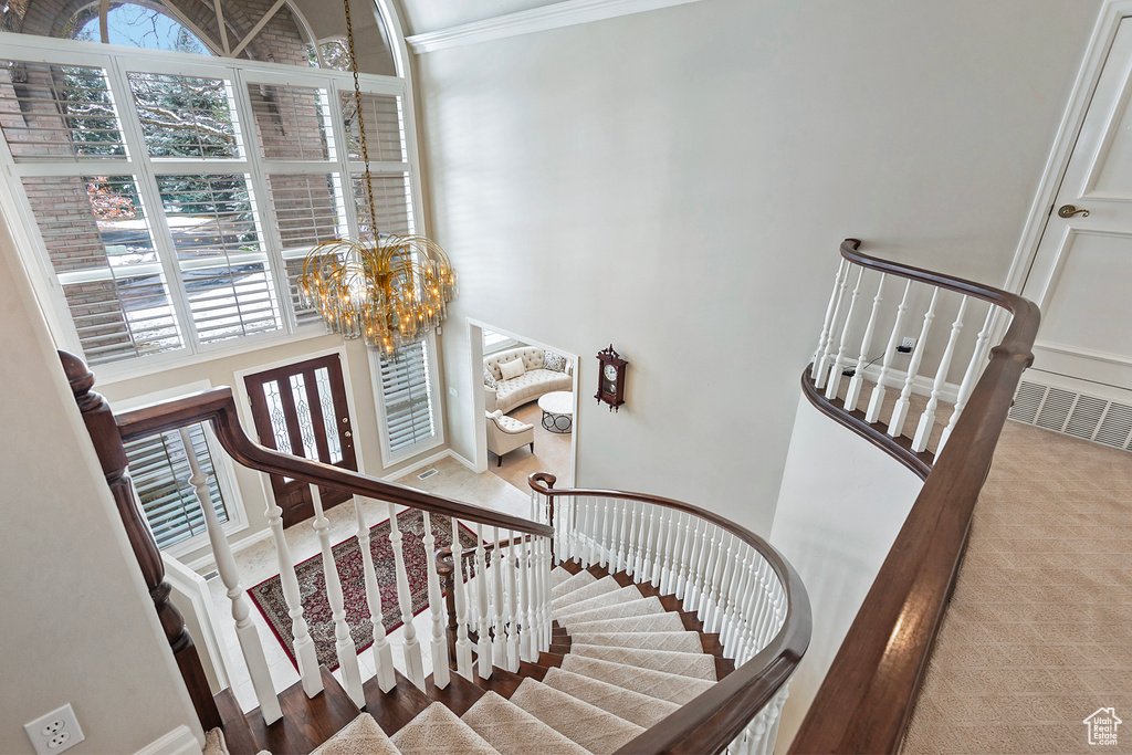 Staircase featuring visible vents, a notable chandelier, and a high ceiling