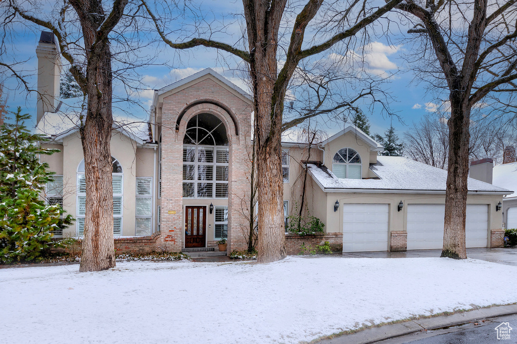 View of front of home featuring a garage, brick siding, and stucco siding