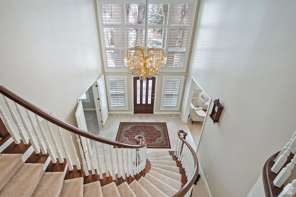 Foyer entrance with a towering ceiling, baseboards, stairs, and a chandelier