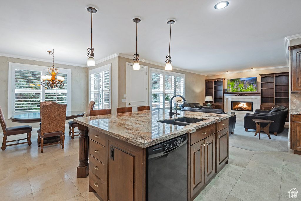 Kitchen featuring a sink, a lit fireplace, dishwasher, a center island with sink, and crown molding