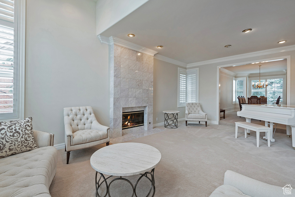 Living area featuring light carpet, baseboards, crown molding, a fireplace, and a notable chandelier