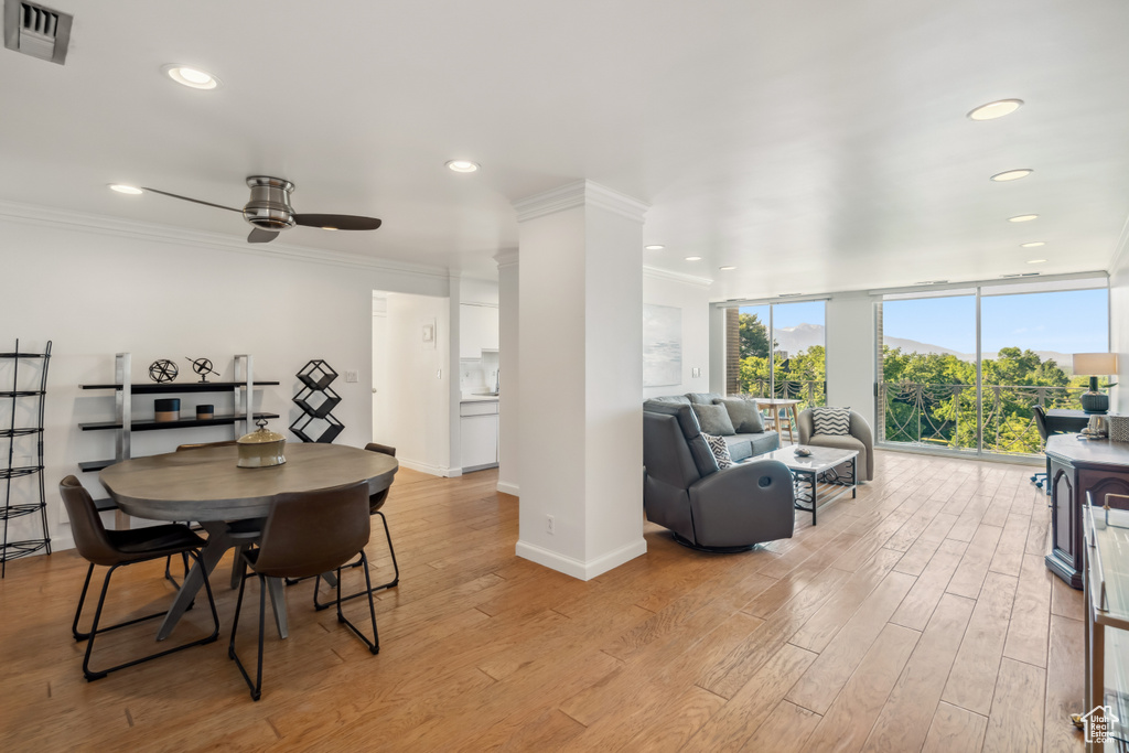 Dining area featuring light wood finished floors, ceiling fan, crown molding, recessed lighting, and ornate columns