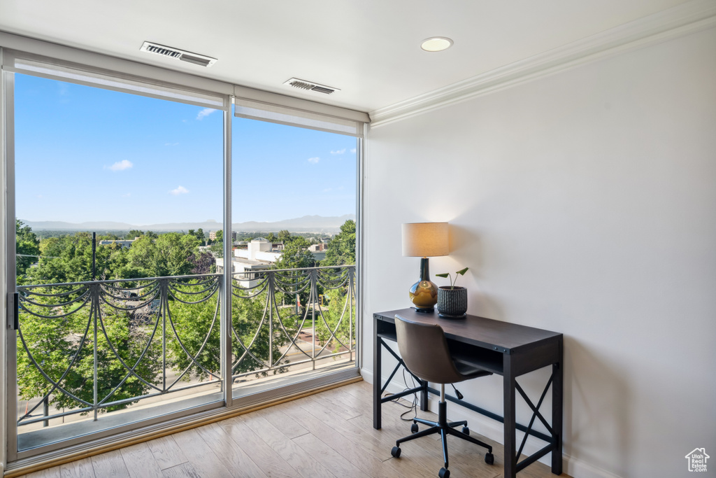 Office area with ornamental molding, a mountain view, wood finished floors, and a wall of windows