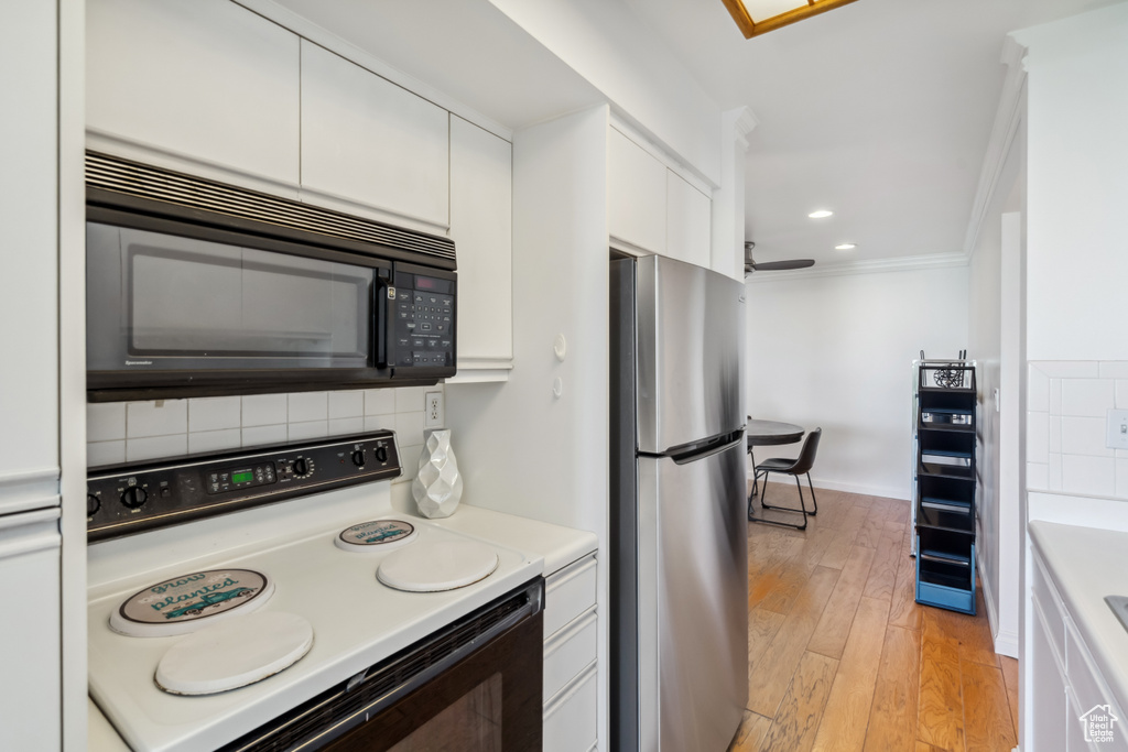 Kitchen featuring freestanding refrigerator, white electric range oven, black microwave, backsplash, and ornamental molding