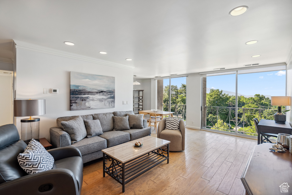 Living room featuring light wood-style flooring, ornamental molding, recessed lighting, and expansive windows