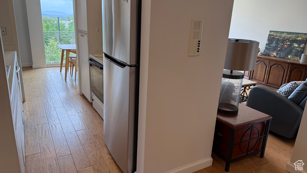 Kitchen featuring freestanding refrigerator, light wood-style floors, baseboards, light countertops, and electric range oven