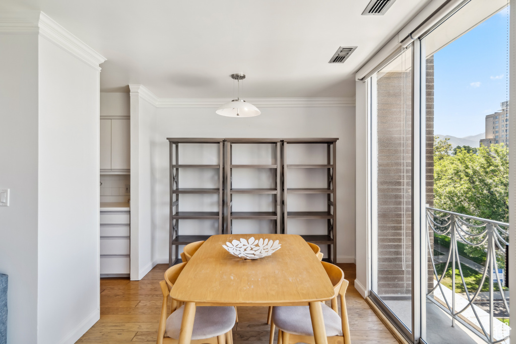 Dining space with plenty of natural light, light wood-type flooring, and ornamental molding