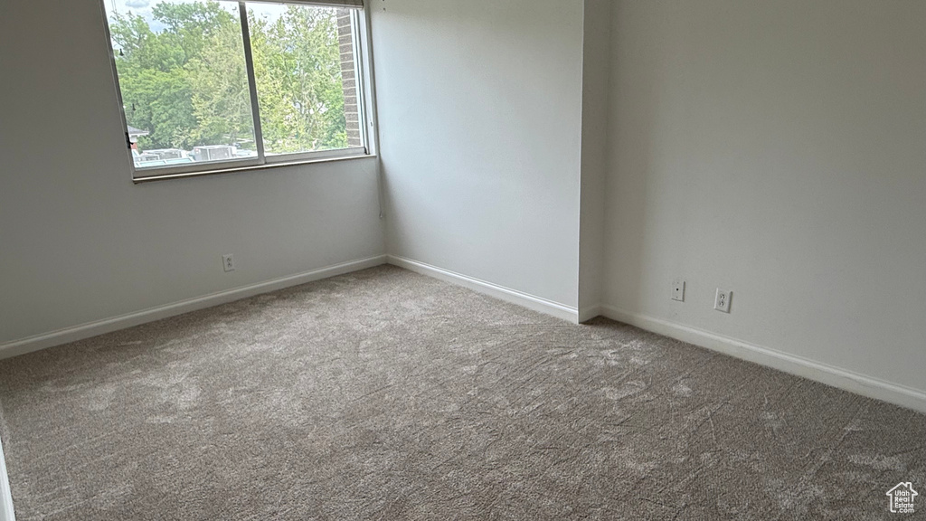 Carpeted spare room featuring baseboards