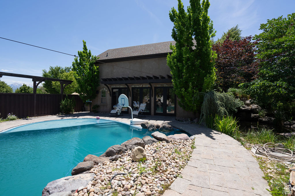 View of swimming pool with french doors and a patio