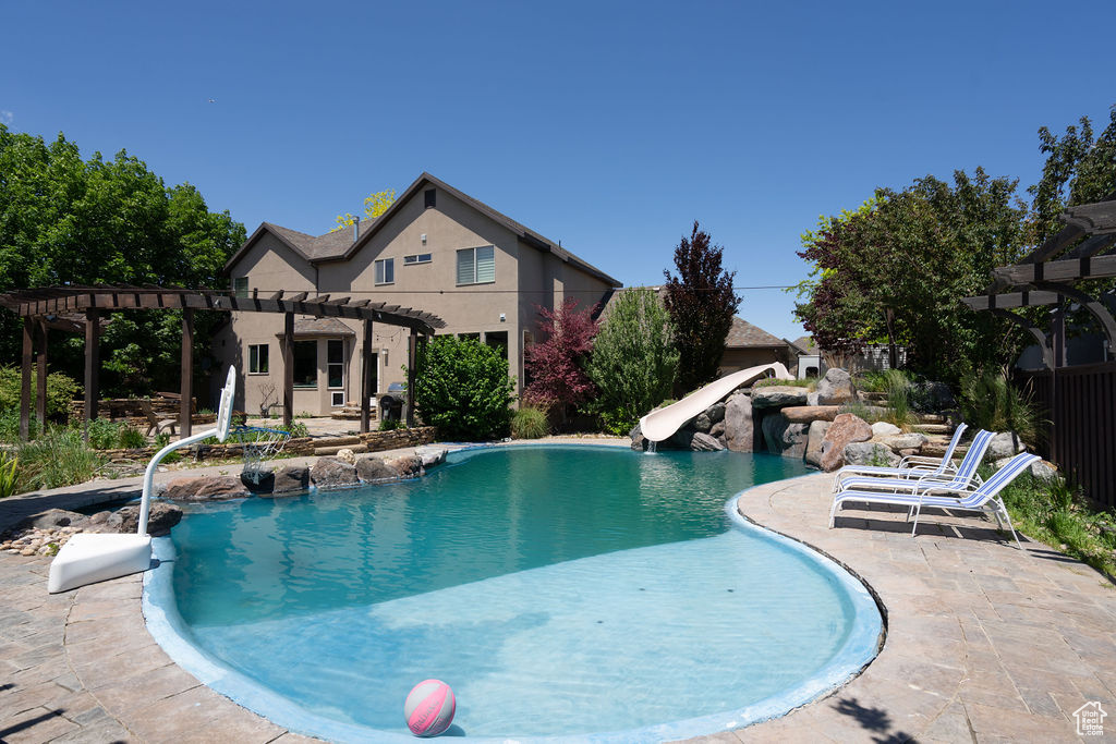 Swimming pool with a pergola, a water slide, and a patio area