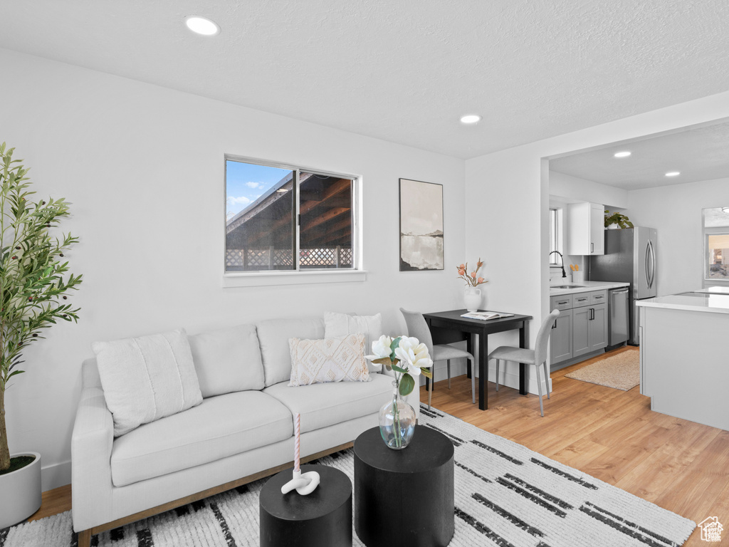 Living room featuring a textured ceiling, light wood-style flooring, and recessed lighting