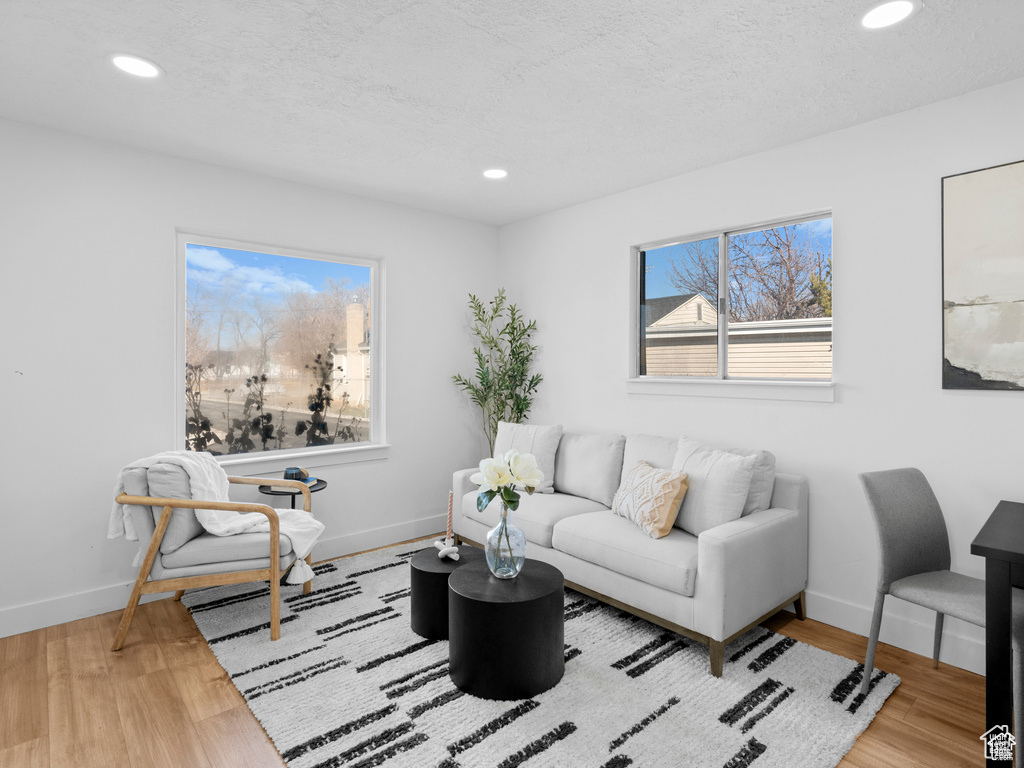 Living area featuring a textured ceiling, recessed lighting, wood finished floors, and baseboards