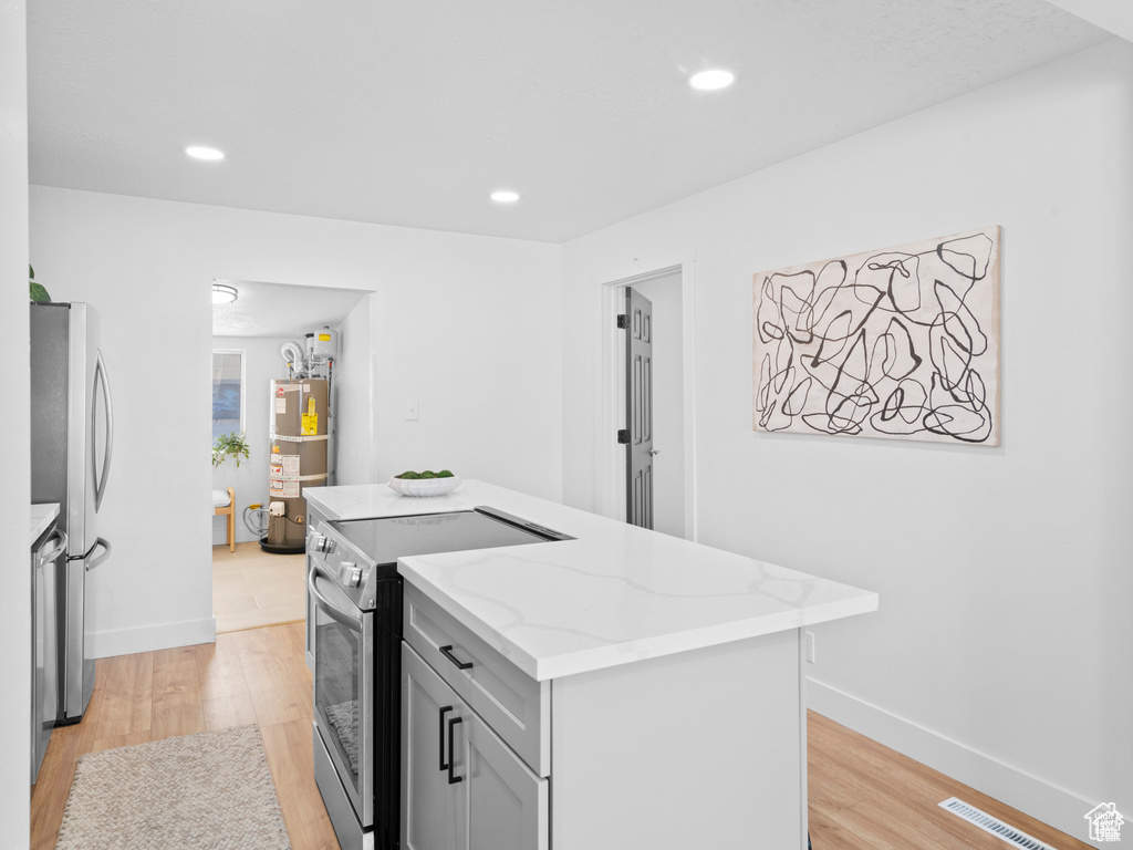 Kitchen with appliances with stainless steel finishes, visible vents, a kitchen island, and light wood-style flooring