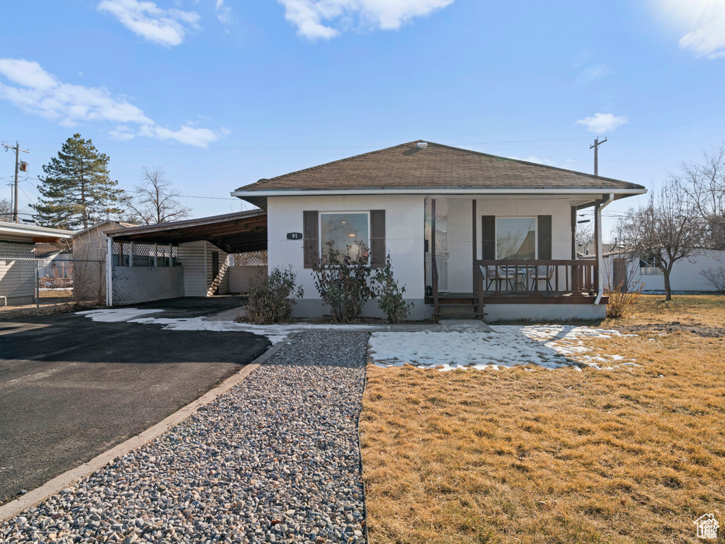 Bungalow-style home featuring driveway, a shingled roof, a porch, a carport, and stucco siding