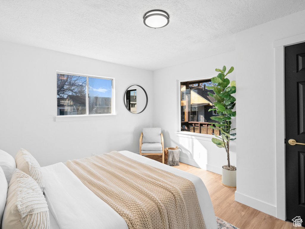 Bedroom with a textured ceiling, wood finished floors, and baseboards