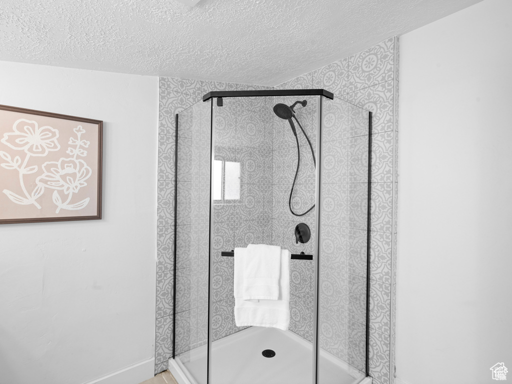 Full bathroom featuring a stall shower and a textured ceiling