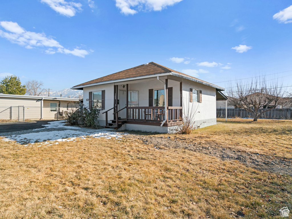 View of front of property featuring covered porch, fence, and a front lawn