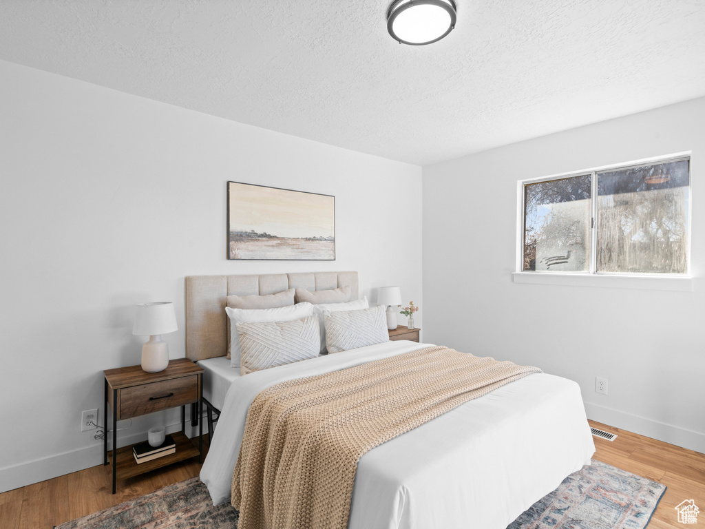 Bedroom with a textured ceiling, baseboards, and wood finished floors