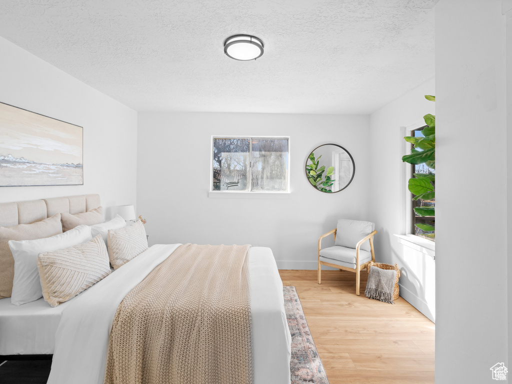 Bedroom featuring a textured ceiling, baseboards, and wood finished floors