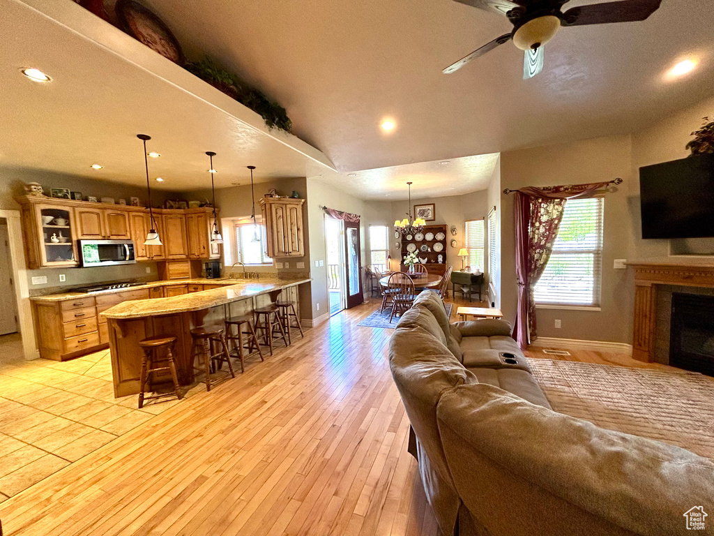 Living area featuring recessed lighting, baseboards, light wood finished floors, and ceiling fan with notable chandelier
