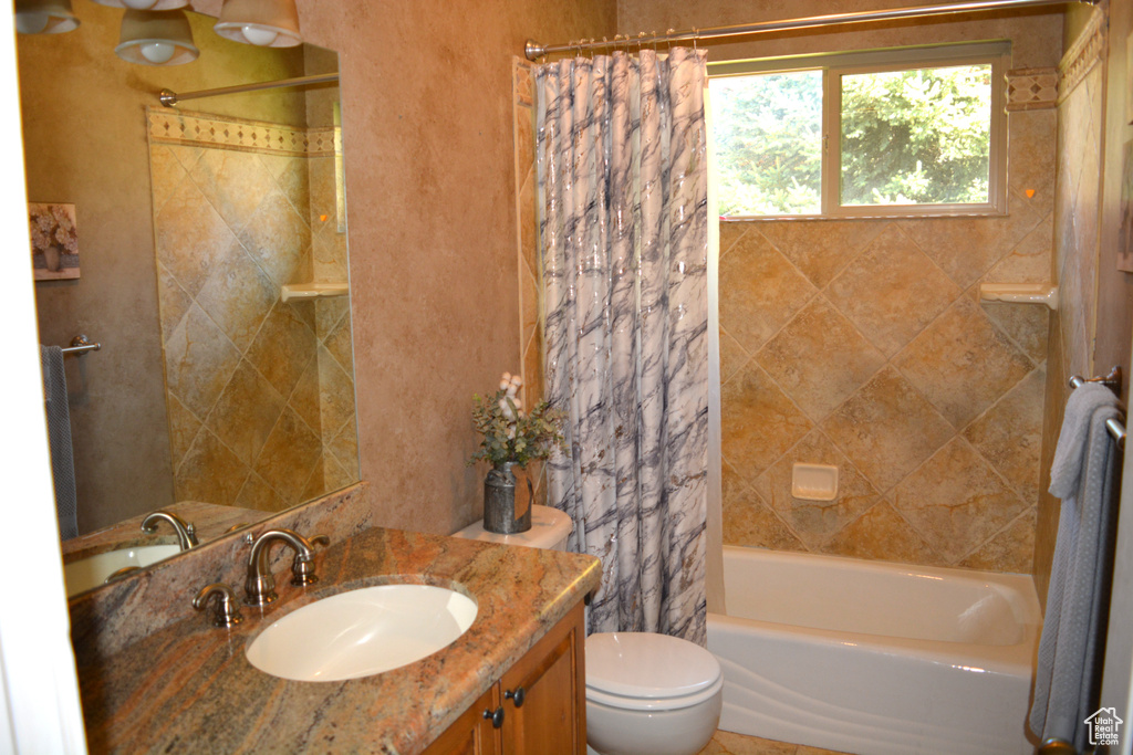 Bathroom with toilet, shower / tub combo with curtain, and vanity